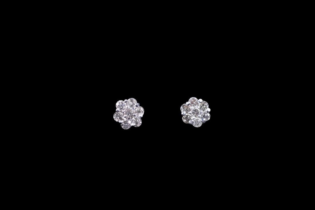 PR 14K GOLD DIAMOND CLUSTER STUD EARRINGS: PR 14K GOLD DIAMOND CLUSTER STUD EARRINGS A pair of 14K white gold stud earrings, each set with (7) round diamonds forming a floral cluster design. The diamonds measure approximately 1.5 mm each. Stam
