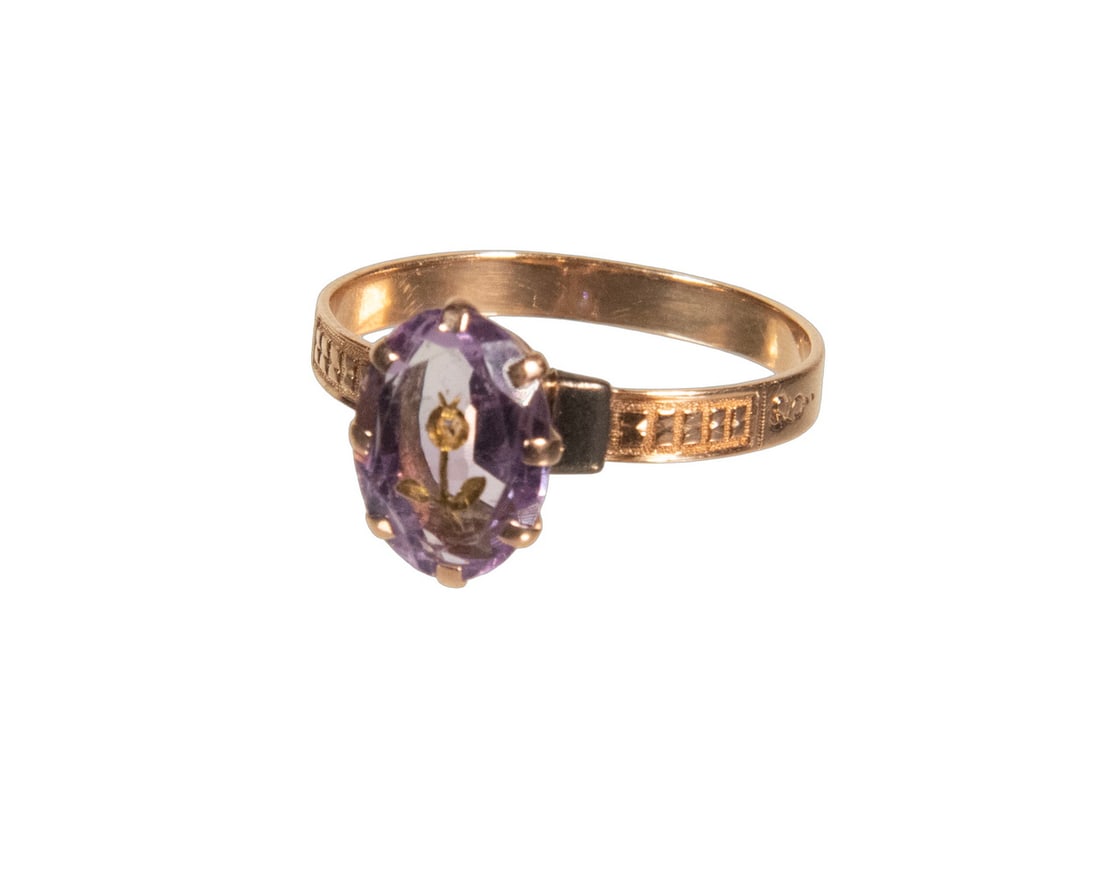 VICTORIAN 10K GOLD AMETHYST AND DIAMOND RING: VICTORIAN 10K GOLD AMETHYST AND DIAMOND RING Set with an oval-cut amethyst applied with a gold floral motif centered by a small single-cut diamond, the engraved shoulders with geometric decoration. 1.