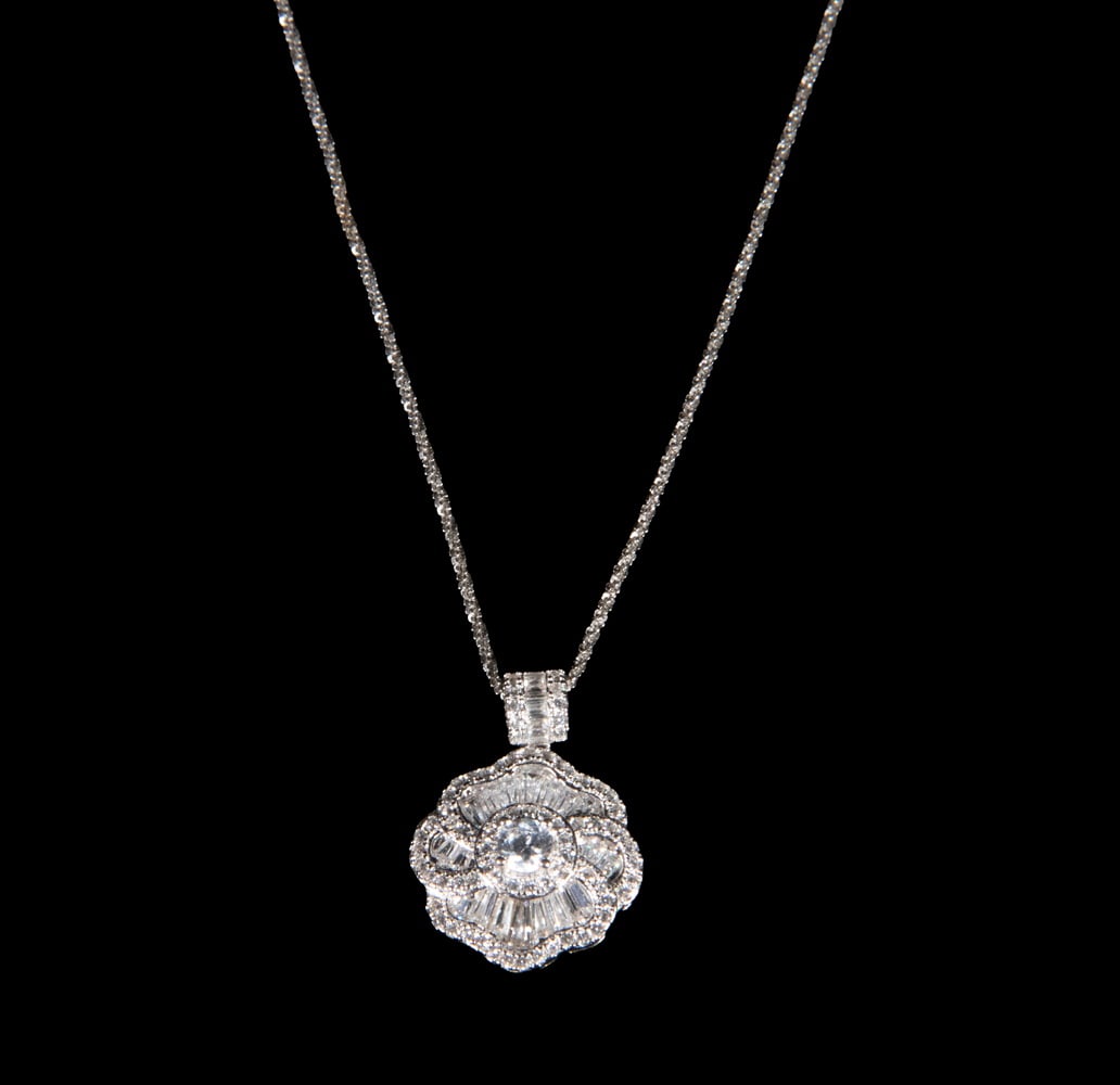 STERLING SILVER NECKLACE SET WITH CUBIC ZIRCONIA: STERLING SILVER NECKLACE SET WITH CUBIC ZIRCONIA A sterling silver necklace featuring a floral-form pendant set with round and baguette-cut cubic zirconia, suspended from a matching silver chain with