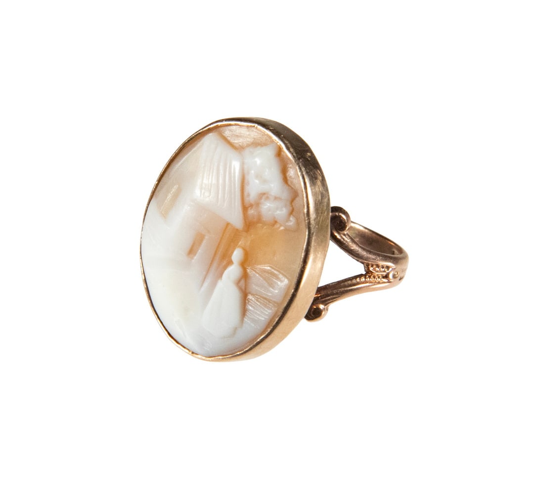 VINTAGE 10K GOLD SHELL CAMEO RING: VINTAGE 10K GOLD SHELL CAMEO RING A 10K gold ring set with an oval carved shell cameo, depicting a figure standing before a house in a landscape setting. The cameo with soft white and warm beige color