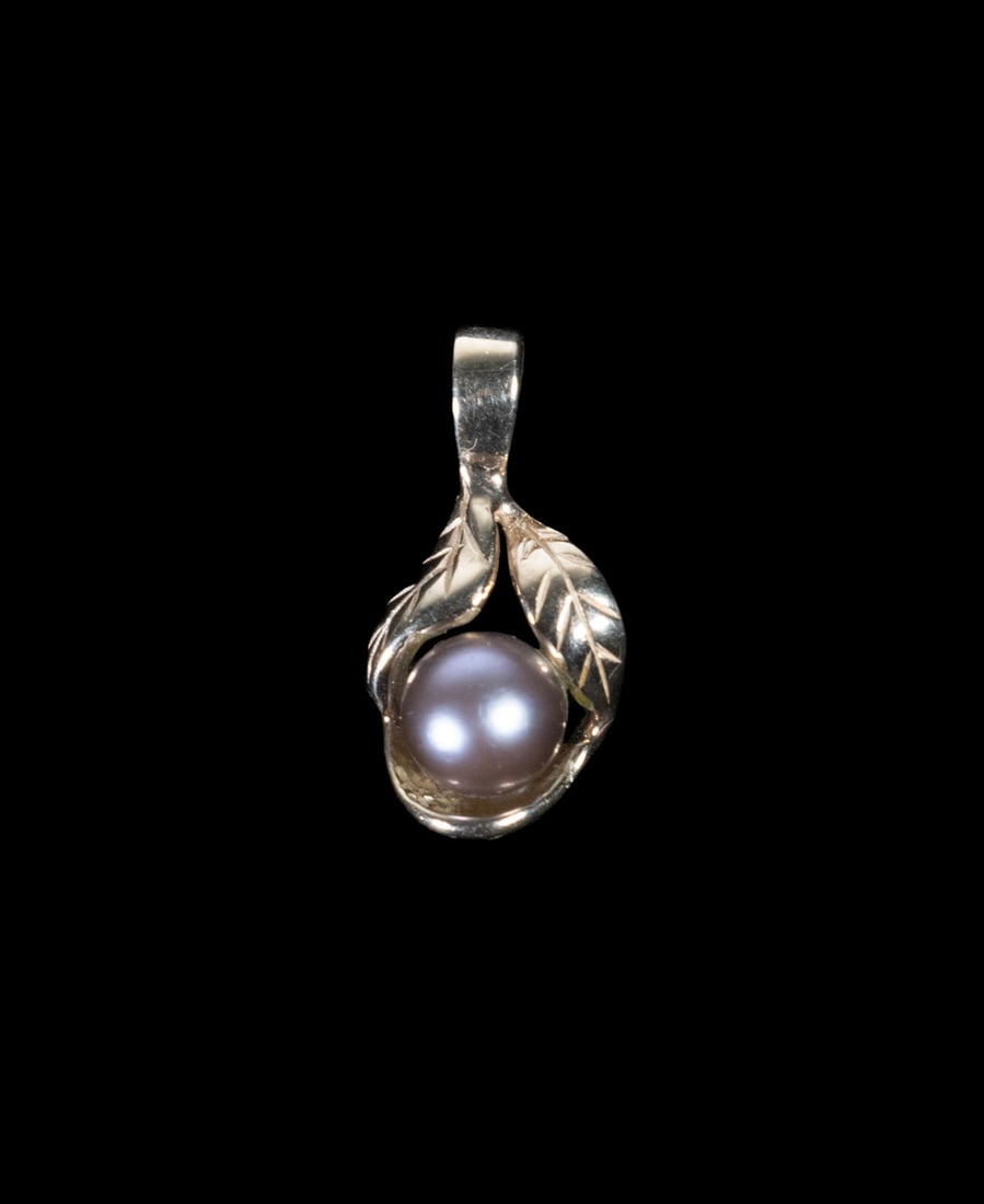 10K GOLD PENDANT WITH GRAY PEARL: 10K GOLD PENDANT WITH GRAY PEARL A 10K yellow gold pendant set with a round warm gray pearl measuring approximately 6.01 mm in diameter, mounted within a stylized leaf-form setting, stamped. 0.9 dwt.
