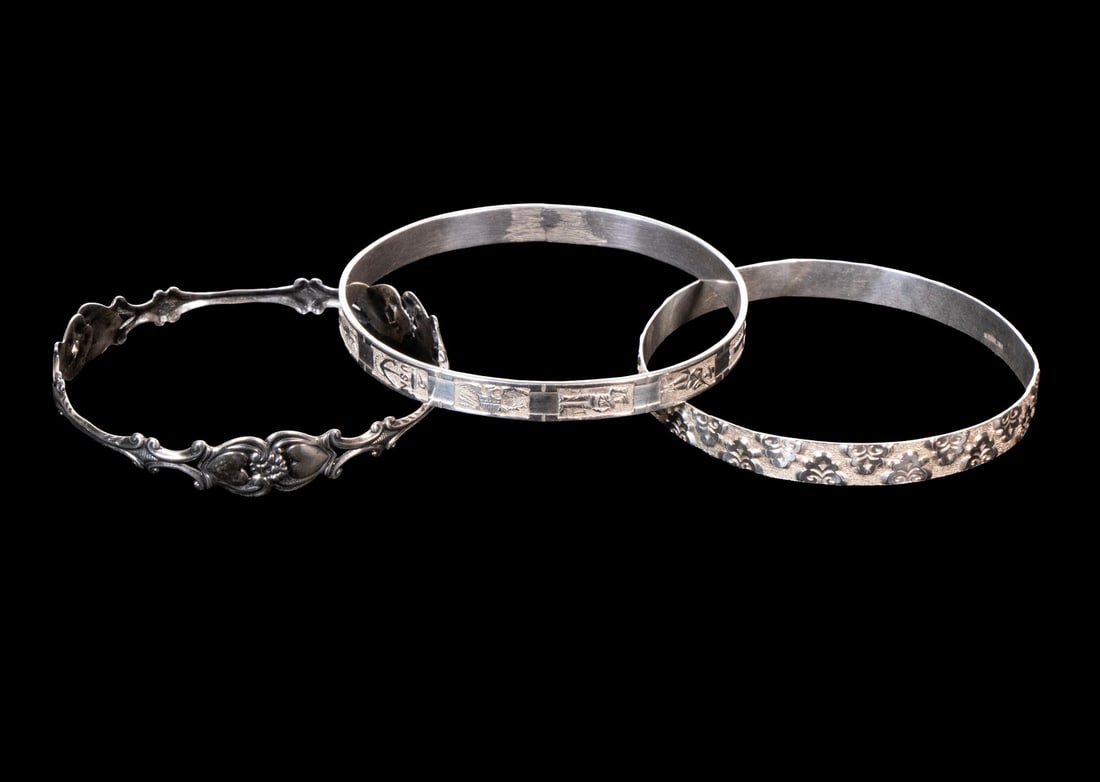 (3) VINTAGE STERLING SILVER BANGLES: (3) VINTAGE STERLING SILVER BANGLES A collection of 3 sterling silver bangles, each with unique decorative designs. One with raised leaf pattern, one with engraved figure and scenic motifs, and one wi