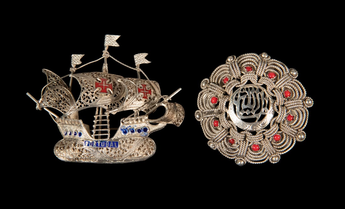 (2) PORTUGUESE FILIGREE SILVER BROOCHES: (2) PORTUGUESE FILIGREE SILVER BROOCHES Including a circular filigree brooch with central monogram and red stone accents, together with a Portuguese filigree caravel brooch decorated with red and blue