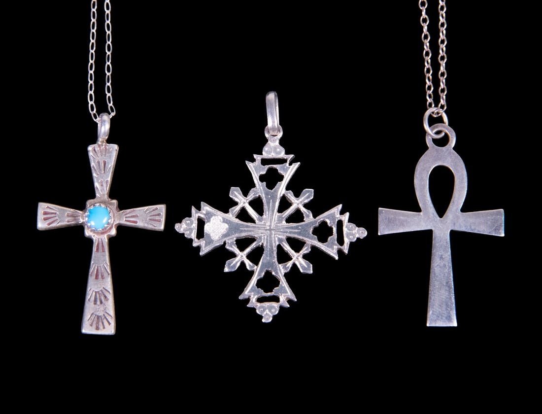 (3) VINTAGE SILVER CROSS JEWELRY ITEMS: (3) VINTAGE SILVER CROSS JEWELRY ITEMS A group including two sterling silver (marked .925) cross pendant necklaces, one set with a turquoise cabochon, together with a .830 silver cross-form pendant.