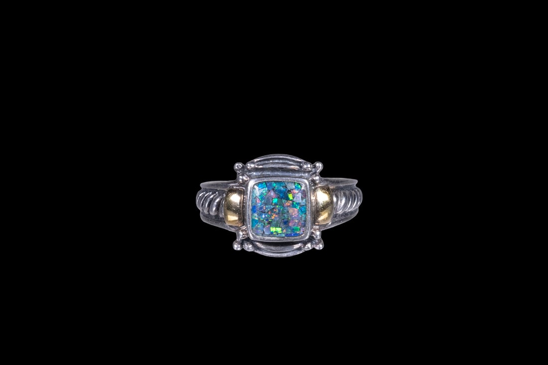 STERLING SILVER AND 14K GOLD OPAL RING: STERLING SILVER AND 14K GOLD OPAL RING A sterling silver ring set with a square-cut doublet opal displaying vibrant play-of-color in flashes of green, orange, and blue. The setting is accented with ye