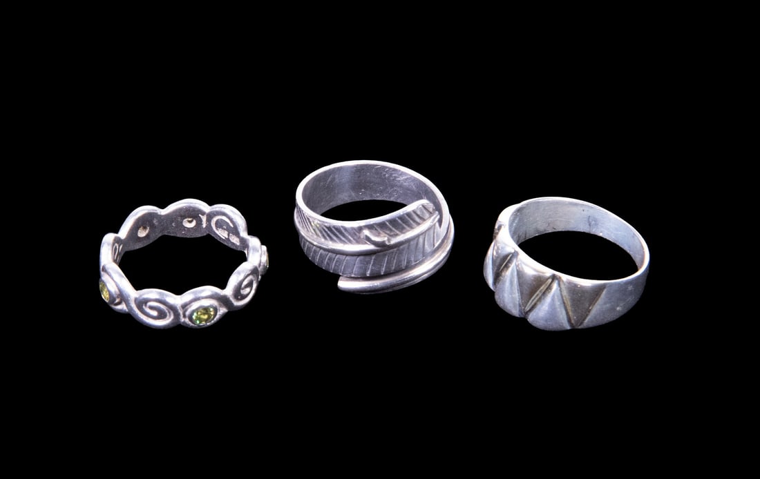 (3) STERLING SILVER RINGS, INCLUDING ADJUSTABLE EXAMPLE: (3) STERLING SILVER RINGS, INCLUDING ADJUSTABLE EXAMPLE A group of three sterling silver rings, including a feather-form adjustable band with engraved detailing and interior signature, a faceted geome