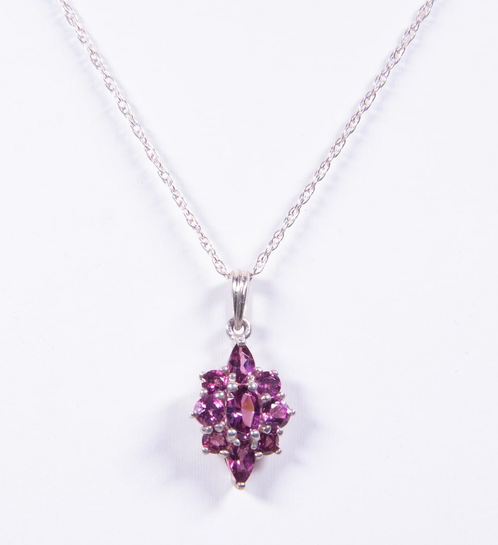 VINTAGE STERLING SILVER GARNET CLUSTER PENDANT NECKLACE: VINTAGE STERLING SILVER GARNET CLUSTER PENDANT NECKLACE A vintage sterling silver necklace featuring a classic cluster pendant set with (9) faceted garnets in a floral arrangement. The stones display