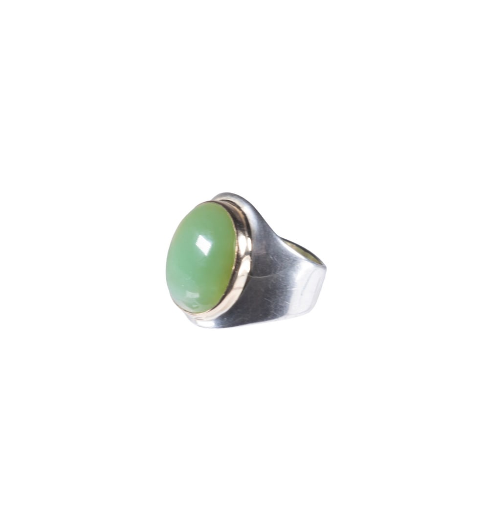 SILVER AND GOLD RING WITH JADE CABOCHON: SILVER AND GOLD RING WITH JADE CABOCHON A contemporary ring set with an oval cabochon jade pale green tone, mounted in a smooth bezel setting of sterling silver, featuring yellow gold around the