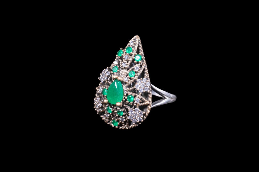 INDIAN-STYLE STERLING SILVER RING WITH SIMULATED GEMSTONES: INDIAN-STYLE STERLING SILVER RING WITH SIMULATED GEMSTONES A large sterling silver ring in an Indian-inspired design, centered by a pear-shaped simulated emerald within an elaborate openwork setting.
