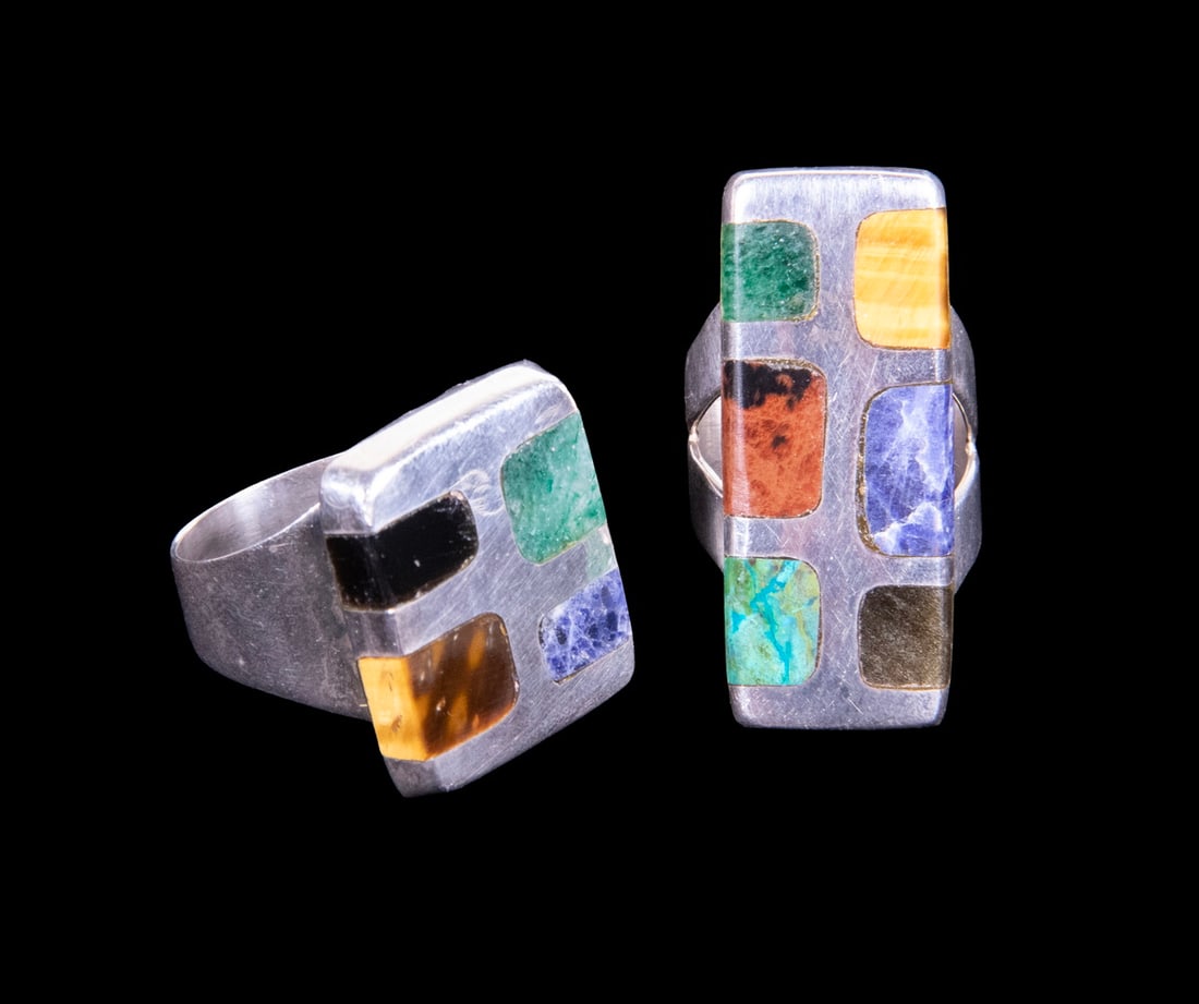 (2) QUINTIN V MEXICAN TAXCO STERLING SILVER MULTI-STONE INLAY RINGS: (2) QUINTIN V MEXICAN TAXCO STERLING SILVER MULTI-STONE INLAY RINGS A pair of Mexican sterling silver rings of bold geometric form, each inlaid with assorted hardstones including sodalite, tiger?s eye