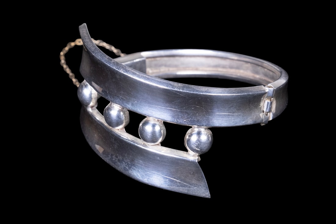 MEXICAN TAXCO STERLING SILVER MODERNIST HINGED BRACELET: MEXICAN TAXCO STERLING SILVER MODERNIST HINGED BRACELET A vintage Mexican sterling silver hinged bracelet in a bold Modernist design, featuring two curved silver bands joined by spherical spacer eleme