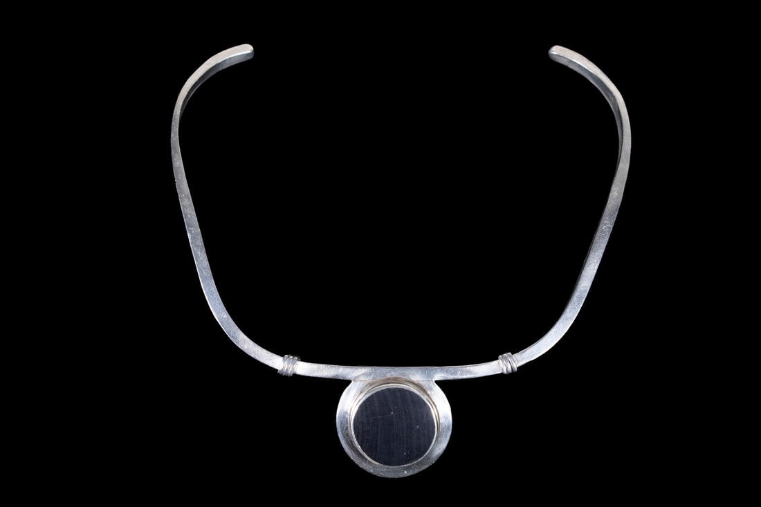MEXICAN MODERNIST STERLING SILVER AND ONYX NECKLACE: MEXICAN MODERNIST STERLING SILVER AND ONYX NECKLACE A modernist sterling silver necklace featuring a circular black onyx panel set within a raised bezel mount. The stone is centered on a shaped open c