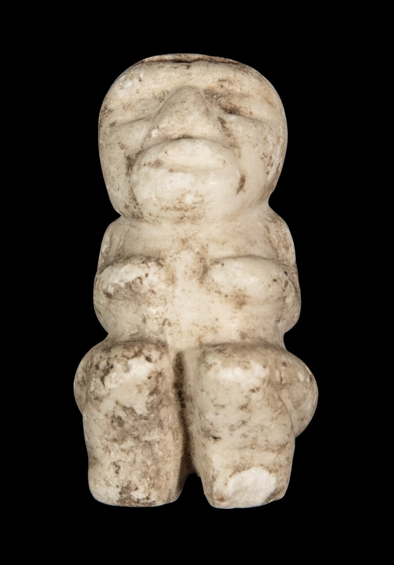 SMALL TAINO WHITE STONE FERTILITY FETISH PENDANT: SMALL TAINO WHITE STONE FERTILITY FETISH PENDANT Squatting Woman with her hands covering her breasts, holes in top of head, Costa Rica. Loss to toes. Size: 2 x 1 x 1 1/4 in. (5.1 x 2.5 x 3.2 cm.)