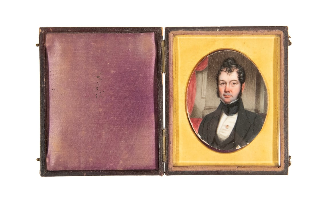 CIRCA 1840 MINIATURE PORTRAIT OF MAN, CASED: CIRCA 1840 MINIATURE PORTRAIT OF MAN, CASED Dignified Gent with curly black hair and sideburns, oil on ivory, unsigned, oval under gilt spandrel and glass, in plain rectangular leather case. Sprung