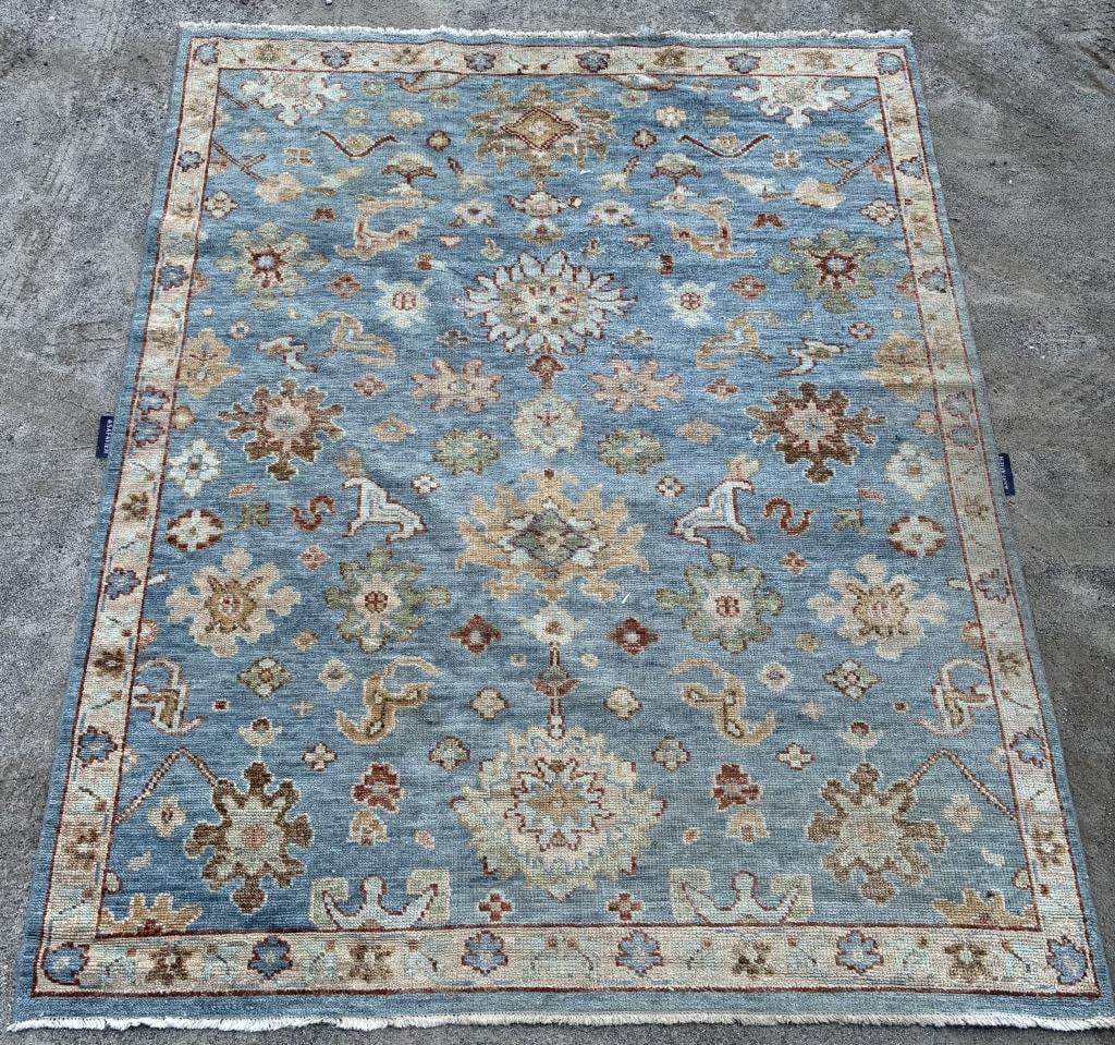ORIENTAL RUG (8' X 10'): ORIENTAL RUG (8' X 10') A large area hooked rug sold by Safavieh. It features a blue field adorned in floral and vine designs with a beige floral border. Overall very good condition. OS: 96 x 120 in.