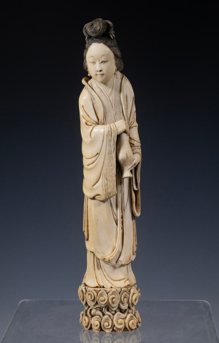 19TH C. CHINESE IVORY FIGURE OF A LADY: Y 19TH C. CHINESE IVORY FIGURE OF A LADY A carved ivory figure depicting a Chinese lady standing in flowing robes with an elaborate coiffure and floral hair ornament. Finely detailed with incised