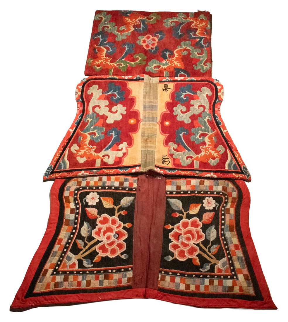 (3) TIBETAN SADDLE RUGS: (3) TIBETAN SADDLE RUGS Comprising three Tibetan wool saddle rugs, including two double-panel examples and one saddle rug panel. One decorated with flowering branches on a black ground, the others wit