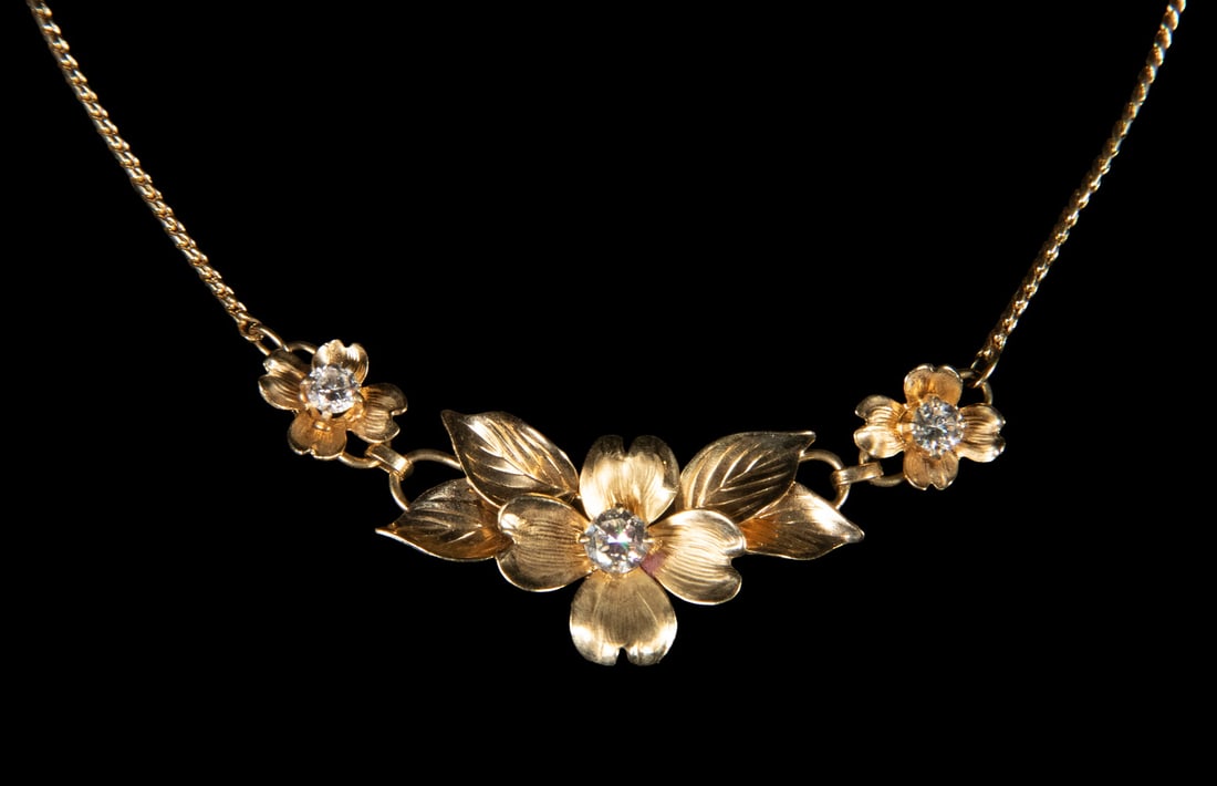 HSB 14K GOLD AND DIAMOND DOGWOOD FLOWER NECKLACE: HSB 14K GOLD AND DIAMOND DOGWOOD FLOWER NECKLACE A vintage 14K gold necklace by HSB, designed with articulated dogwood blossoms and engraved leaves suspended from a curb link chain. Set with (3)