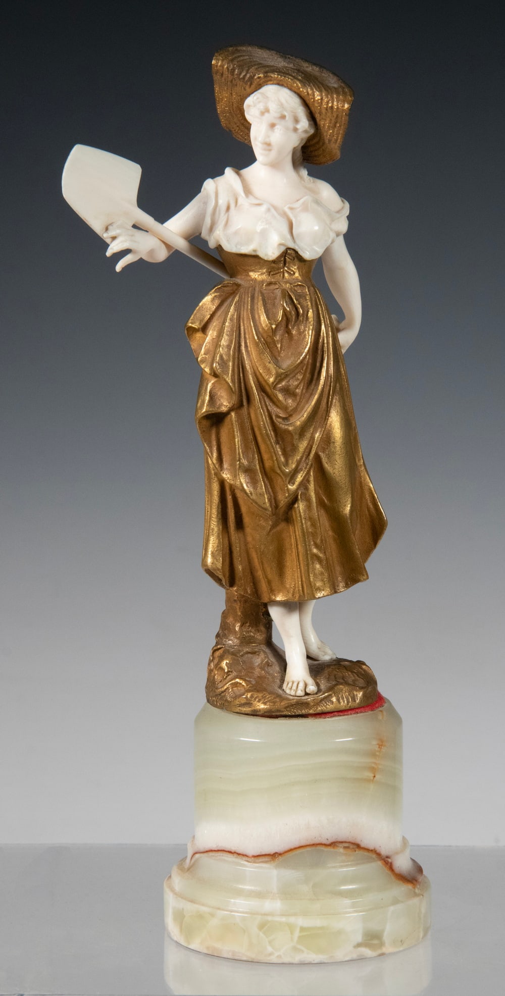 GLADENBECK BRONZE AND IVORY FIGURE: Y GLADENBECK BRONZE AND IVORY FIGURE Girl in Fields with Straw Hat and Shovel, gilt bronze with ivory, artist unknown, but marked by Aktien-Gesellschaft Gladenbeck Foundry (Berlin, Germany), which