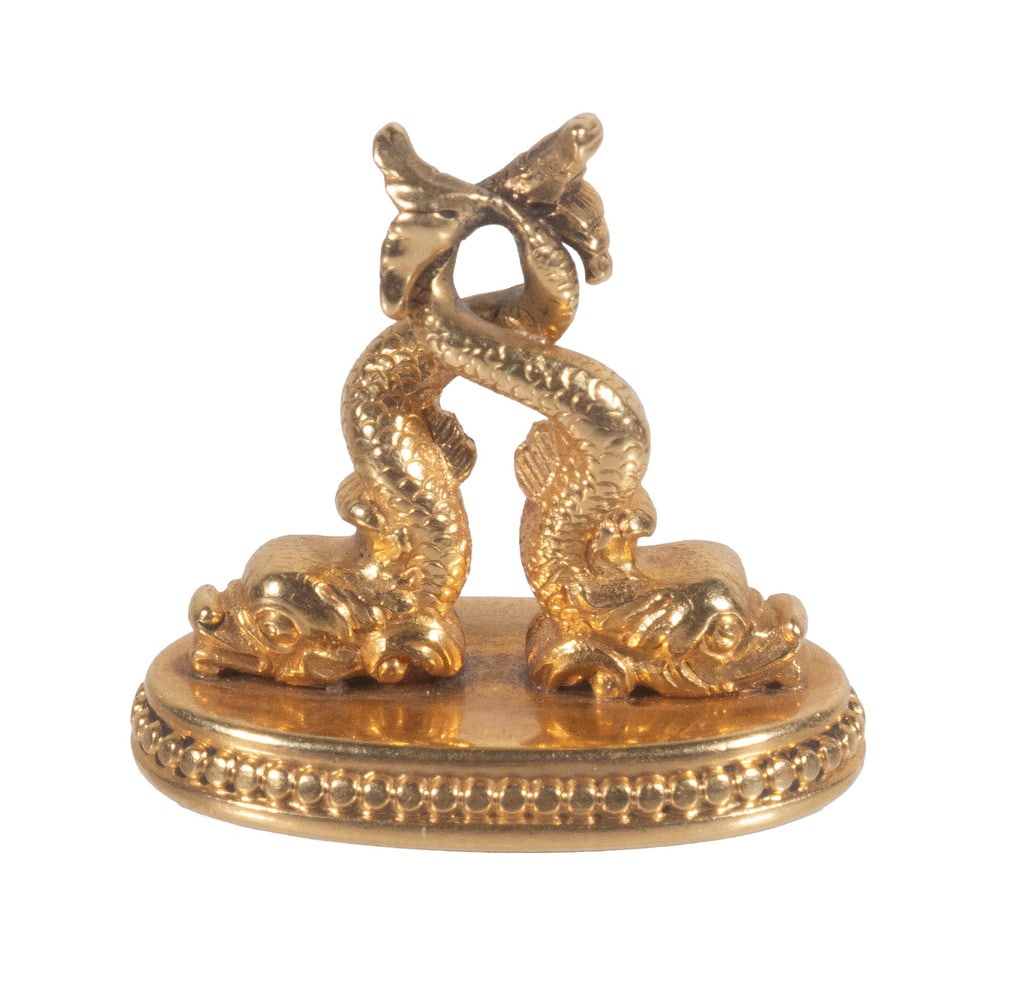 18K GOLD AND CARNELIAN WATCH FOB SEAL: 18K GOLD AND CARNELIAN WATCH FOB SEAL The oval carnelian seal mounted in an 18K yellow gold setting surmounted by a pair of dolphin-dragons, the bezel with beaded border decoration. The seal appears u