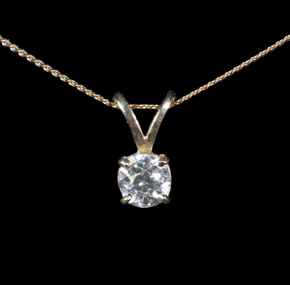 14K GOLD AND DIAMOND PENDANT NECKLACE: 14K GOLD AND DIAMOND PENDANT NECKLACE Comprised of a fine 14K yellow gold chain necklace suspending a solitaire round brilliant-cut diamond pendant in four-prong setting. The diamond measures