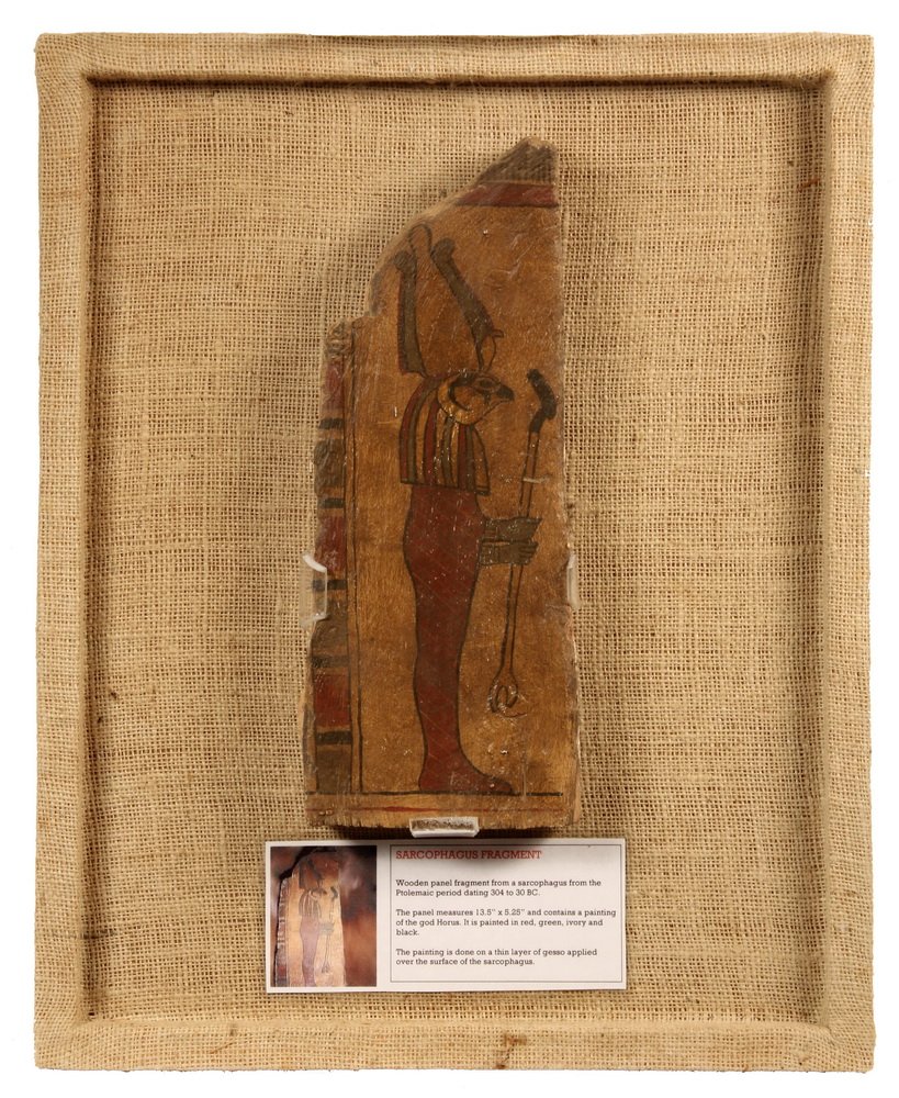 EGYPTIAN SARCOPHAGUS FRAGMENT - Ptolemic Period (304 to: EGYPTIAN SARCOPHAGUS FRAGMENT - Ptolemic Period (304 to 30 BC) Painted Wood Portrait of the God Horus holding a staff, mounted in plexi case with burlap backing. 20" x 16" x 3" overall. 13 1/2" x 5 1/