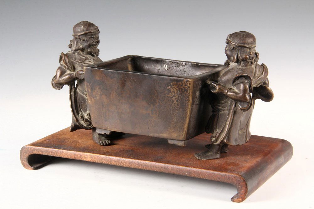 CHINESE BRONZE FIGURAL PLANTER ON STAND - Two Servants: CHINESE BRONZE FIGURAL PLANTER ON STAND - Two Servants Carrying a Large Oblong Footed Planter, signed on underneath, the men are laughing at each other under the strain. 18th c. On hardwood stand. 8"