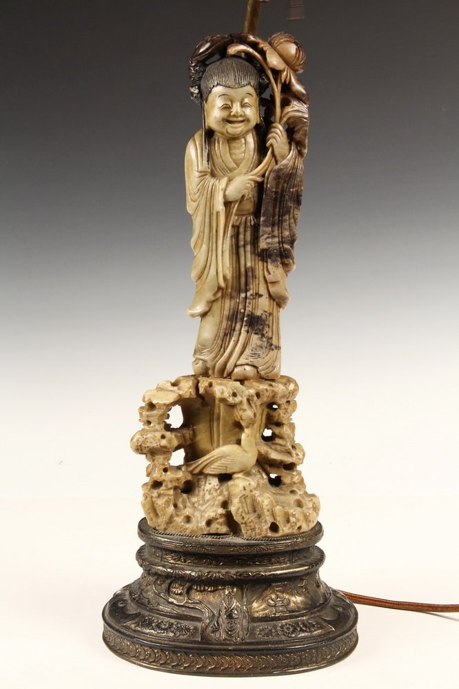 CHINESE STONE CARVING AS LAMP BASE - 1920s Vintage: CHINESE STONE CARVING AS LAMP BASE - 1920s Vintage Soapstone Carving of Laughing Woman holding flower, standing atop a landscape with bird, mounted on gilt bronze base with double socket stem. 26" tal