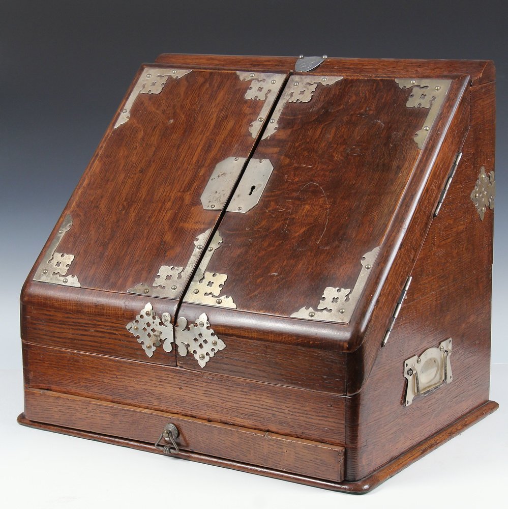 ENGLISH DESK BOX - Oak Slant Front Writing Box with: ENGLISH DESK BOX - Oak Slant Front Writing Box with silver fittings, sterling 'JC' shield at top hallmarked Birmingham,1924, William Aitken. The locking box with compartments, inkwells and drawer belo