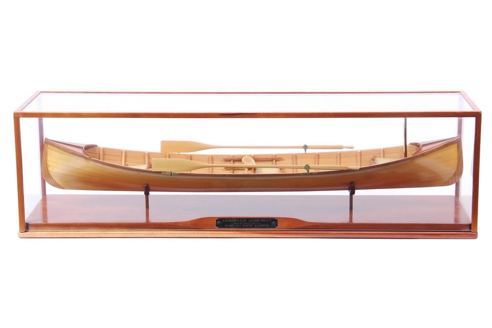 CUSTOM BOAT MODEL - "Adirondack Guide Boat" modeled by: CUSTOM BOAT MODEL - "Adirondack Guide Boat" modeled by David Kavner, Keene, NY. In original glass case with name plate. Fully planked scale model set loose in yoke stand. 25 1/2" x 7" x 6 1/2" case. 2