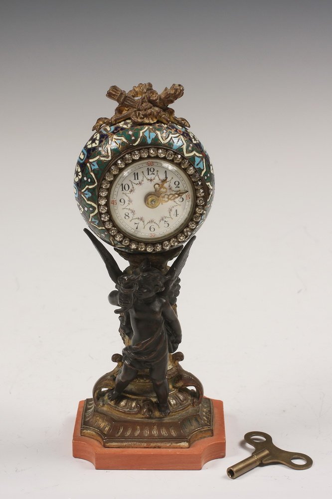 FRENCH CHAMPLEVE CLOCK - Late 19th c. French Vanity: FRENCH CHAMPLEVE CLOCK - Late 19th c. French Vanity Clock in gilt bronze with a champlevé housing, having a column set on pink stone plinth, fronted by a cherub holding a torch aloft, surmounted by t