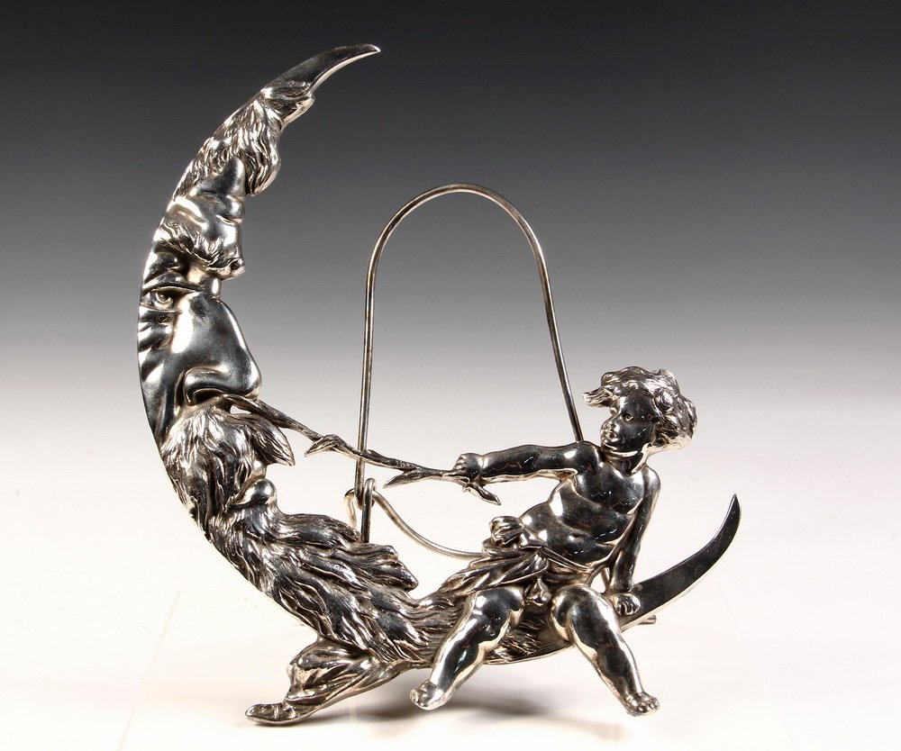 SILVER PLATE MIRROR FRAME - Rogers Silver Tabletop: SILVER PLATE MIRROR FRAME - Rogers Silver Tabletop Mirror Stand depicting a Putti tickling the nose of the Old Man on the Moon, perhaps a New Years allegory? 13" tall. Lacking round mirror glass.
