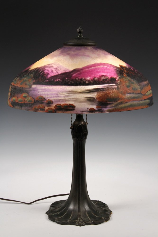 ART GLASS TABLE LAMP - Bronze Finish Trunk Form Base: ART GLASS TABLE LAMP - Bronze Finish Trunk Form Base with domed glass shade having brushed texture, depicting mountains with lakes, fields of flowers, bright sunset sky. Unmarked. Ca 1920. Bead chain 