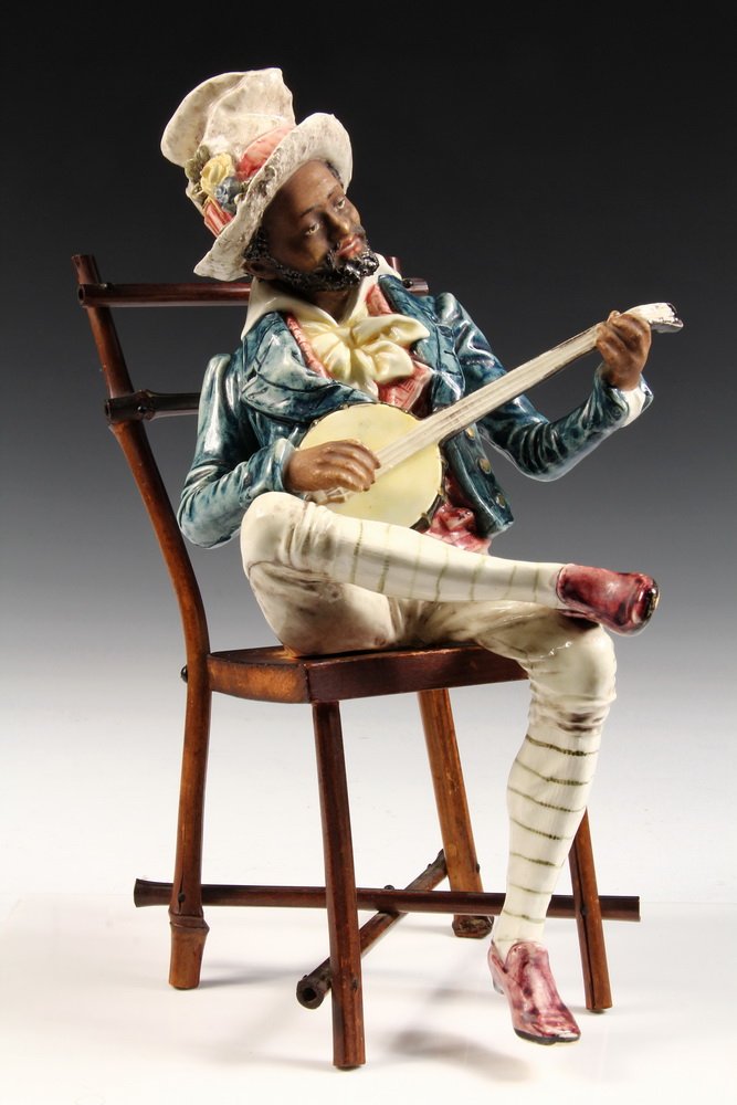 MAJOLICA FIGURE - 19th c. Austrian Majolica Portrait of: MAJOLICA FIGURE - 19th c. Austrian Majolica Portrait of a seated African-American banjo player in full regalia of top hat, waist-coat, vest & cravat, breeches & leggings, pink shoes. With original bam