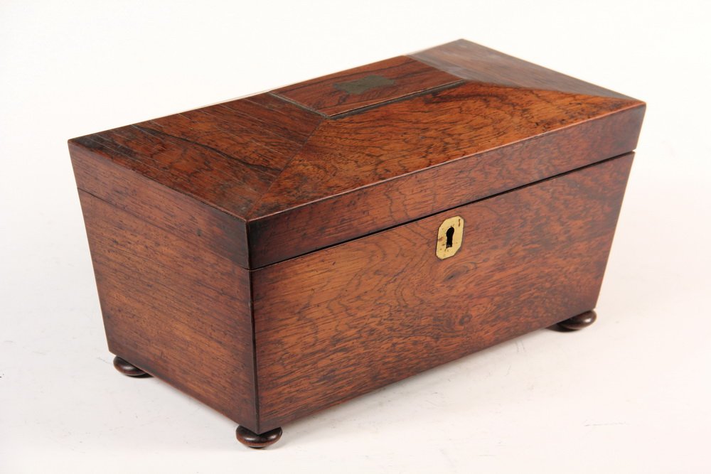 ENGLISH TEA CADDY - Regency Rosewood Casket Form Tea: ENGLISH TEA CADDY - Regency Rosewood Casket Form Tea Caddy, brass top plate & escutcheon, bun feet (one missing), two covered compartments, receptacle for glass mixing bowl (missing). 6" x 11" x 5 1/2