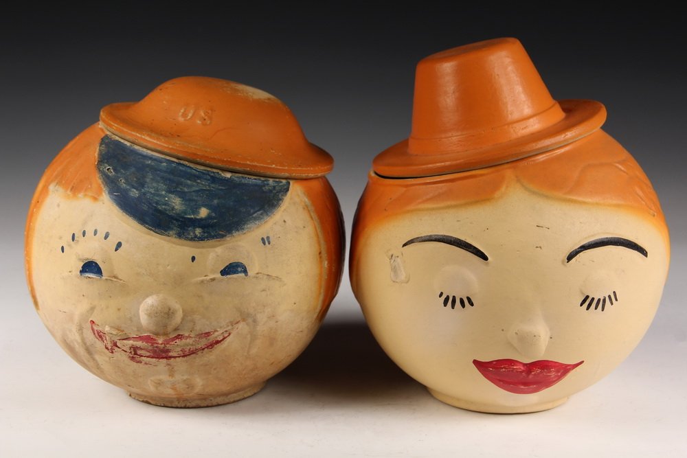 (2) FIGURAL COOKIE JARS - Roly-Poly Heads of a Man and: (2) FIGURAL COOKIE JARS - Roly-Poly Heads of a Man and Woman, in partially glazed stoneware, in blue, orange and red. 8 1/2" & 9" tall. Some wear. Repair to woman's hat (lid).