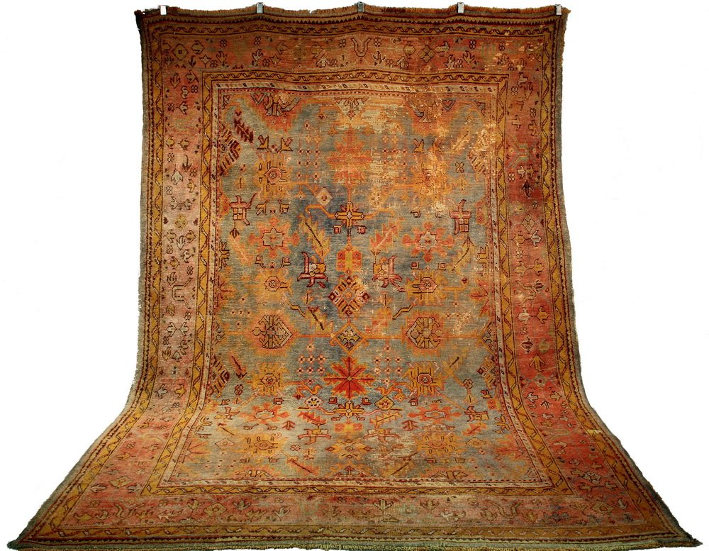 USHAK CARPET - 8 1/2' x 12' - West Anatolia, overall: USHAK CARPET - 8 1/2' x 12' - West Anatolia, overall design of large serrated leaves, palmettes and rosettes in rust red, gold, brown and tan. Set on an abrashed light blue-green field, flowerhead and