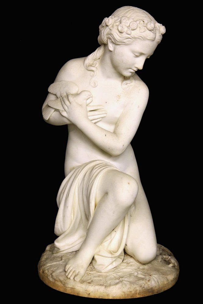 PASQUALE ROMANELLI (Italy, 1812-1887), Aphrodite with: PASQUALE ROMANELLI (Italy, 1812-1887), Aphrodite with Dove to Breast, Kneeling on a Snake, in white marble, signed left rear of the integral plinth. 35 1/2" tall. Slightly weathered, bird beak tip mis
