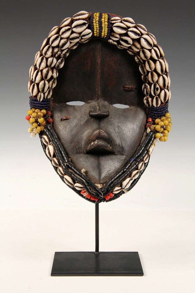 AFRICAN MASK - Dan Peoples Dancing Mask , Ivory Coast,: AFRICAN MASK - Dan Peoples Dancing Mask , Ivory Coast, Liberia, in wood with metal teeth, with cowrie shell and glass bead trim. On museum stand. 11" tall. Very good condition.