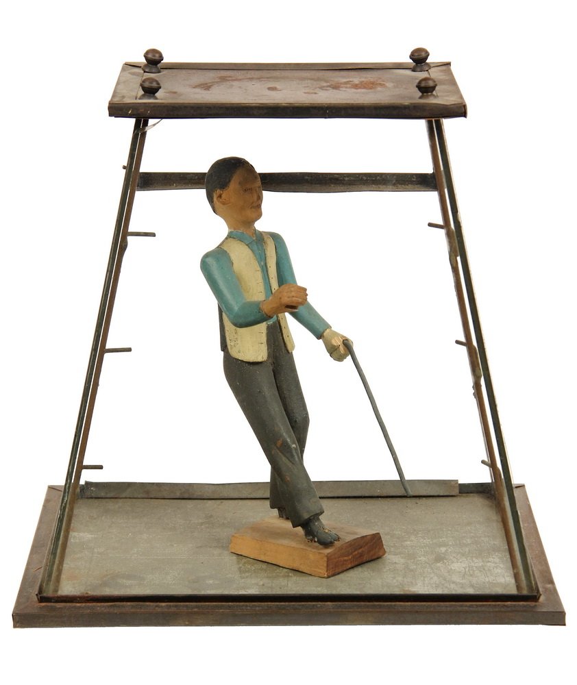 FOLK ART CARVING - Figure of a Man Walking with a Cane: FOLK ART CARVING - Figure of a Man Walking with a Cane and a Newspaper, circa 1910, in painted pine, 8 1/2" tall, inside vintage tin and glass store display cabinet, 11" x 8" x 11". Good condition.