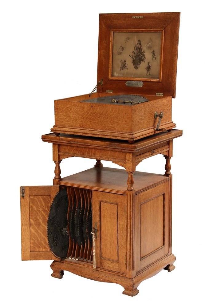 MUSIC BOX ON ORIGINAL STAND WITH (38) DISCS - Wurlitzer: MUSIC BOX ON ORIGINAL STAND WITH (38) DISCS - Wurlitzer Regina, 15 1/2" disc, in golden oak case with original paper label, in working condition, with crank; PLUS the original golden oak stand with ra