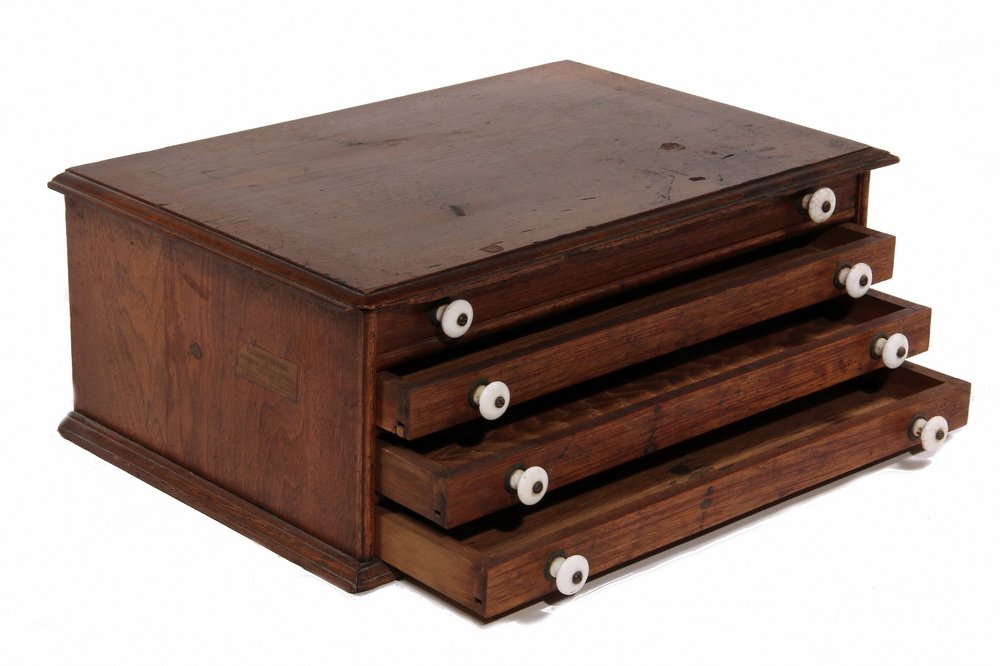 SPOOL CABINET - Four Drawer Mahogany Cabinet with: SPOOL CABINET - Four Drawer Mahogany Cabinet with overhanging molded top, molded foot, ceramic knobs. 8" x 13 1/4" x 20 1/2". Stain to top and face, chips and corner loss to moldings.