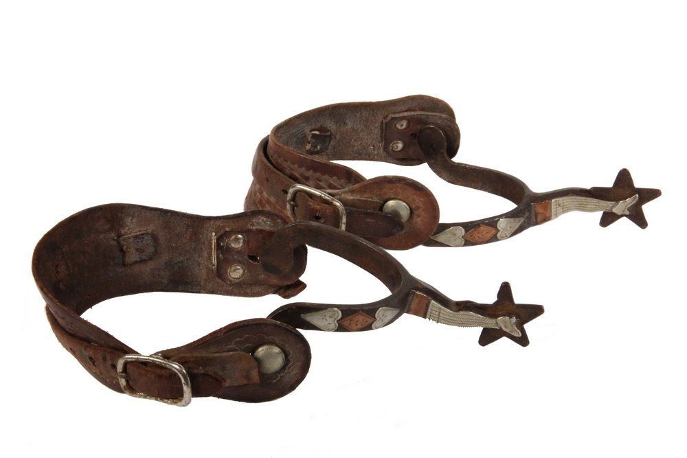 PAIR OF 19TH C AMERICAN WESTERN SPURS - Circa 1870-80: PAIR OF 19TH C AMERICAN WESTERN SPURS - Circa 1870-80 Iron Hand Cut Five-Point Star Spurs with chased silver and copper mounts in the form of a woman's leg in stocking and shoe, a pair of hearts flank
