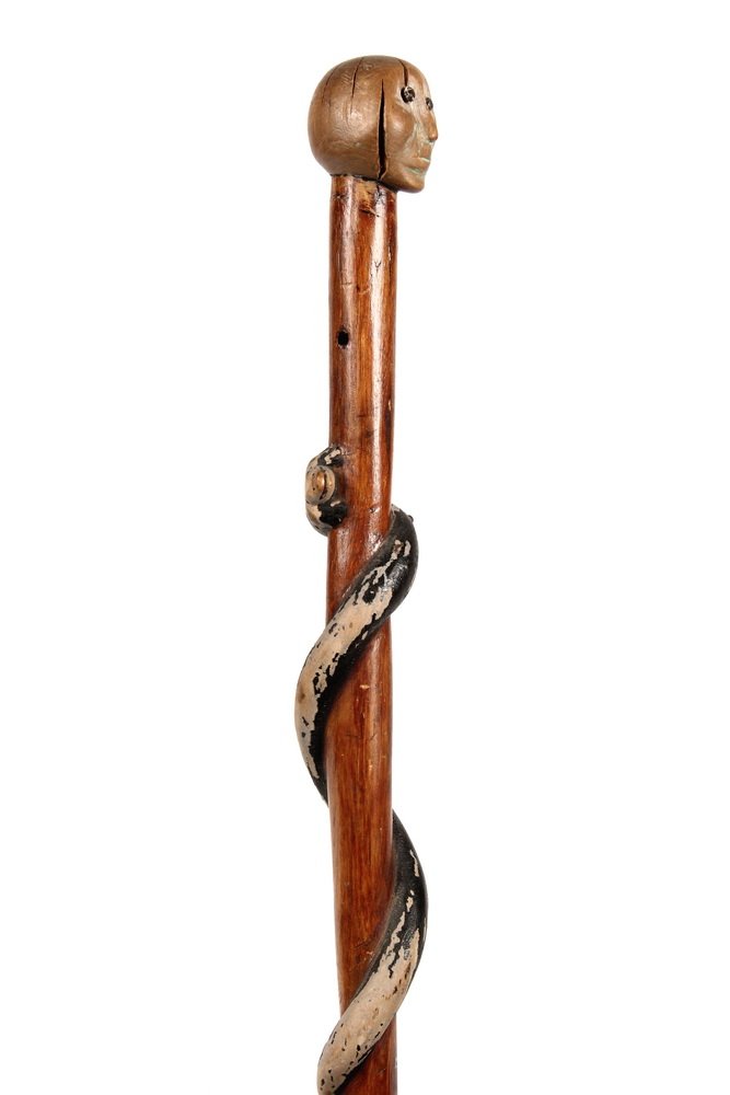 NATIVE AMERICAN WALKING STICK - 19th c Iroquois Maple: NATIVE AMERICAN WALKING STICK - 19th c Iroquois Maple Cane carved with a human head handle having tack eyes and remnants of white and green paint, the tapered and varnished shaft ending in a brass fer