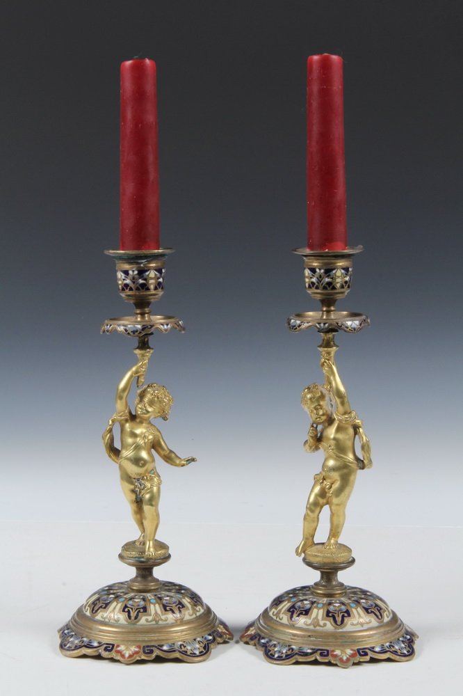 PAIR CHAMPLEVE CANDLESTICKS - Pair of Enameled Gilt: PAIR CHAMPLEVE CANDLESTICKS - Pair of Enameled Gilt Brass Cherub Form Candlesticks, probably French, circa 1880s, unmarked. 8 3/4" tall. Fine condition.