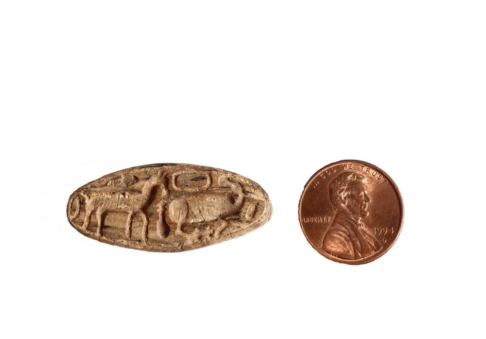 ANCIENT EGYPTIAN BEAD - Buff Faience Seal Bead in: ANCIENT EGYPTIAN BEAD - Buff Faience Seal Bead in elongated ovoid form, featuring glyphs of a horse, an antelope and a fish. 1 1/2" long. Good condition.