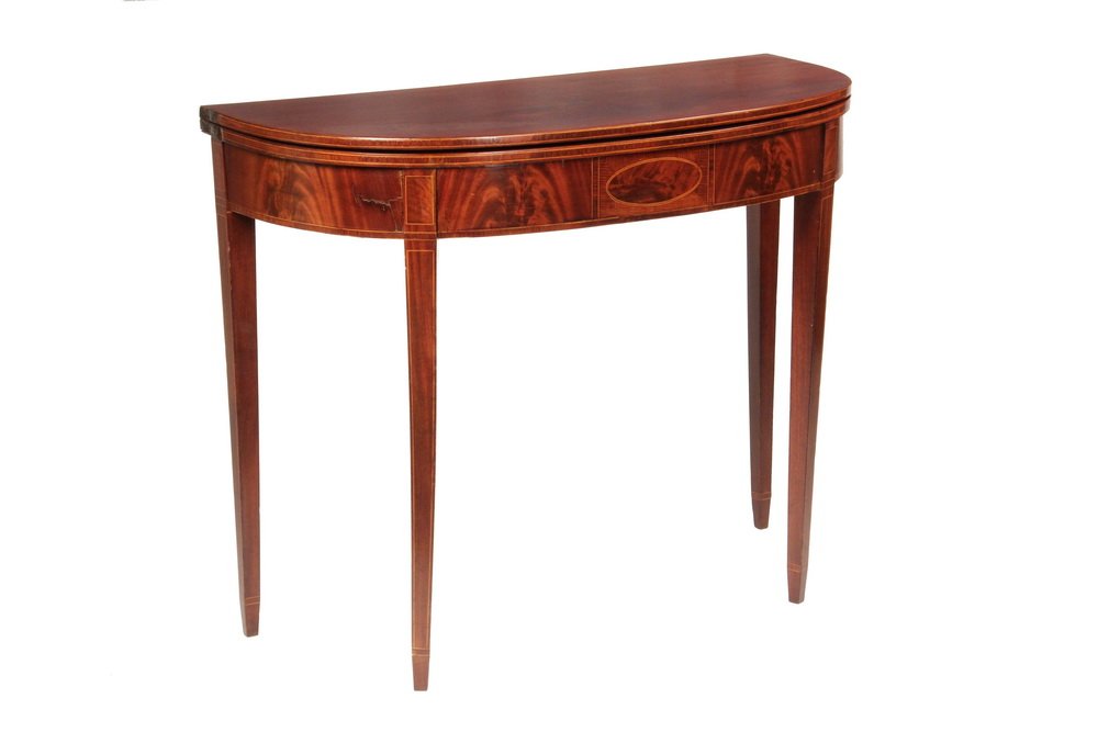 CARD TABLE - Boston Area Hepplewhite Mahogany Card: CARD TABLE - Boston Area Hepplewhite Mahogany Card Table in demilune form. The top having a hinged leaf and inlaid edge, conforming shaped frieze and crotched flame grained mahogany, with a central ov