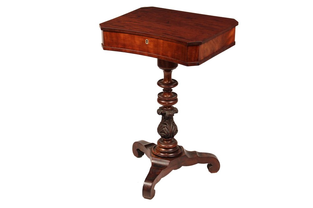 SEWING STAND - Mid 19th c. Mahogany Stand with: SEWING STAND - Mid 19th c. Mahogany Stand with overhanging hinged lid, inner compartments, oblong case with canted corners, concave front, turned column with carved acanthus leaf urn, set on platform 