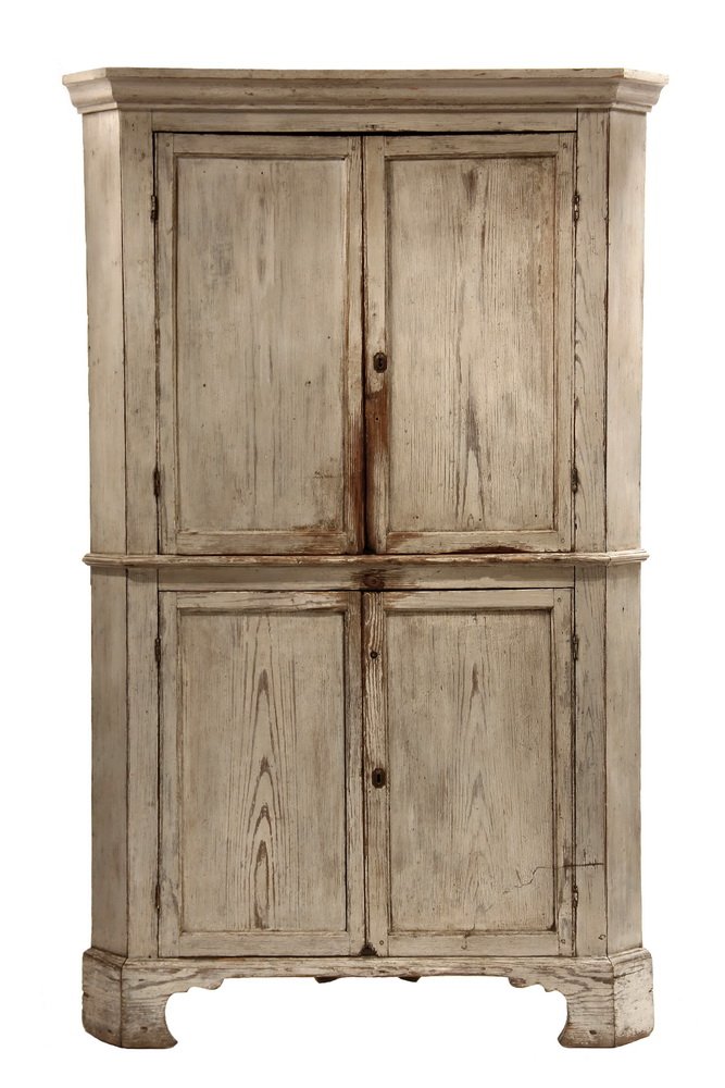 CONTINENTAL CORNER CUPBOARD - Early Pine Cupboard in: CONTINENTAL CORNER CUPBOARD - Early Pine Cupboard in whitewash, with molded cornice, two sets of recessed panel doors, two upper and one lower shelf, molded waist and shaped bracket base. 79" x 46" x 