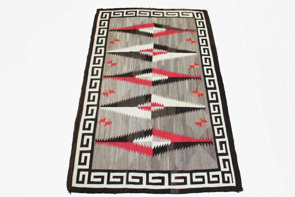 NATIVE AMERICAN RUG - Two Grey Hills Navajo Rug, circa: NATIVE AMERICAN RUG - Two Grey Hills Navajo Rug, circa 1900, in sand, tan, ochre, brown, red and cream, with gradiation within the forms, key border, 62" x 96", minor edge loss, some holes.